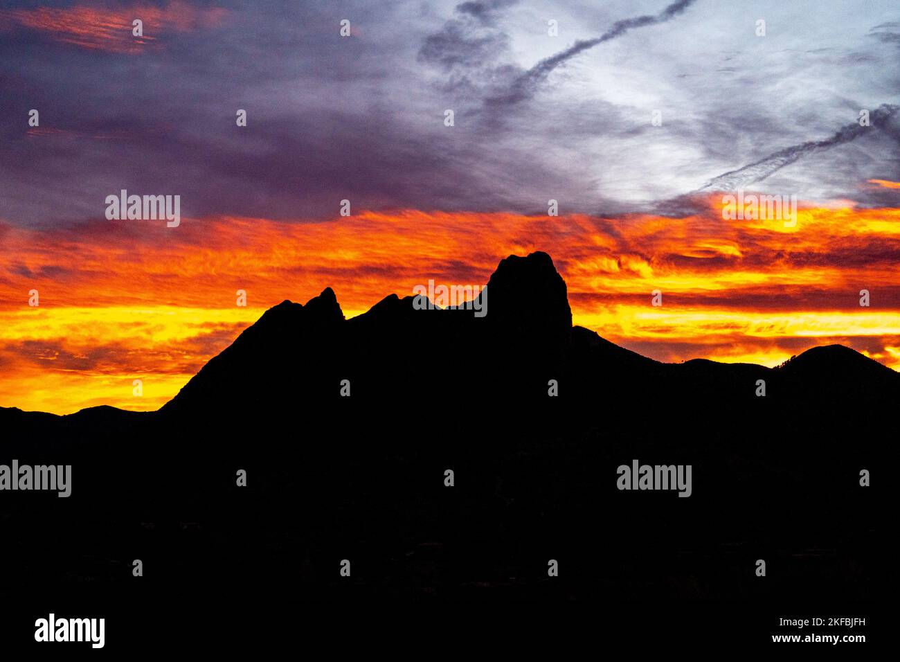 Orange cloudy sky with silhouette of a mountain Stock Photo