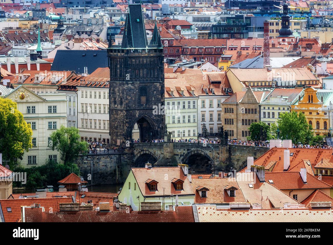 Tiled roofs of the city of Prague and a fragment of the Charles Bridge over the Vltava River. Stock Photo