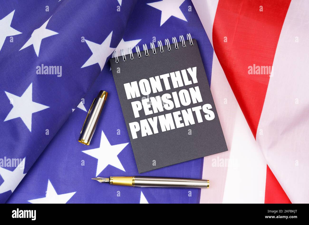 Business concept. On the American flag lies a pen and a notebook with the inscription - monthly pension payments Stock Photo