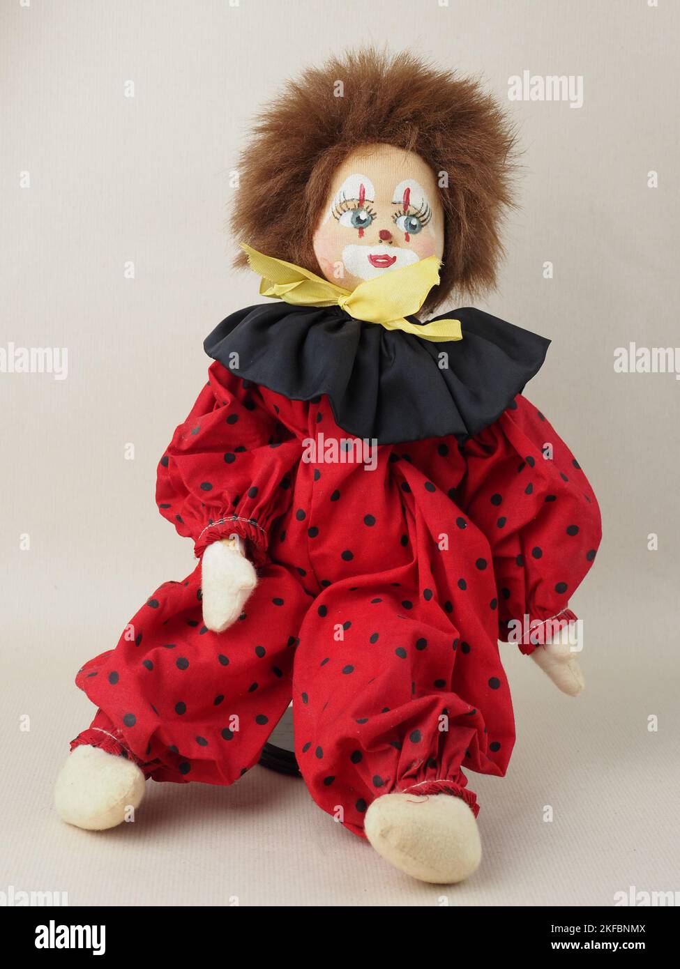 Vintage red-haired clown doll in a red suit with a black collar. Stock Photo