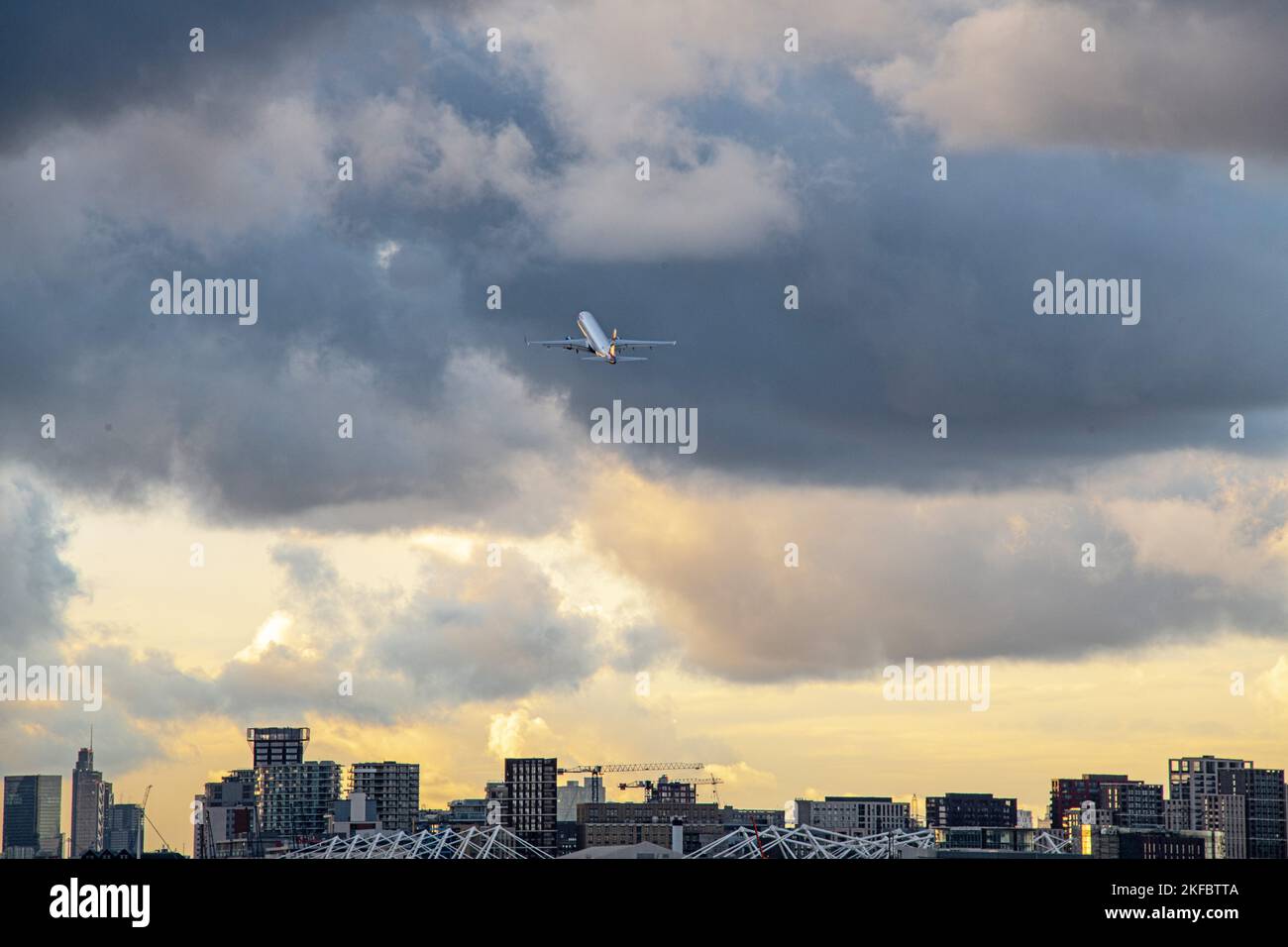 A British Airways Embraer ERJ-190 climbs steeply into stormy skies after take off from London City Airport. Stock Photo