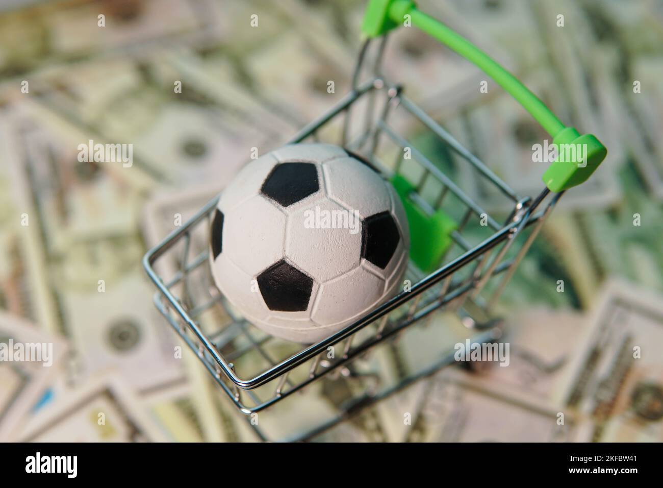 Soccer ball in shopping cart on usa dollar banknotes background