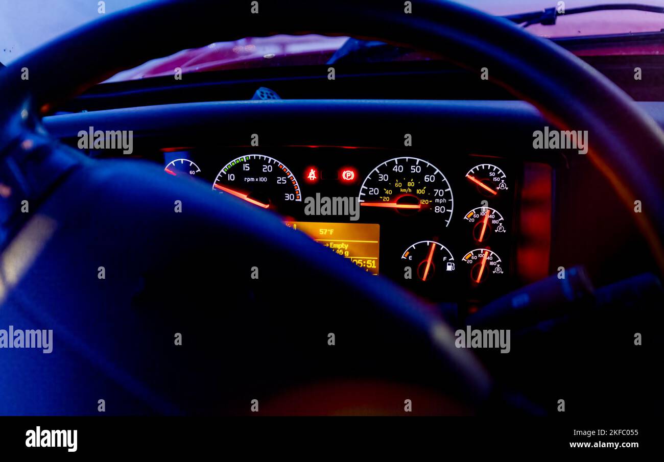 Modern American semi truck dashboard seen thru steering wheel with dash bezels light up, dark, evening scene Stock Photo