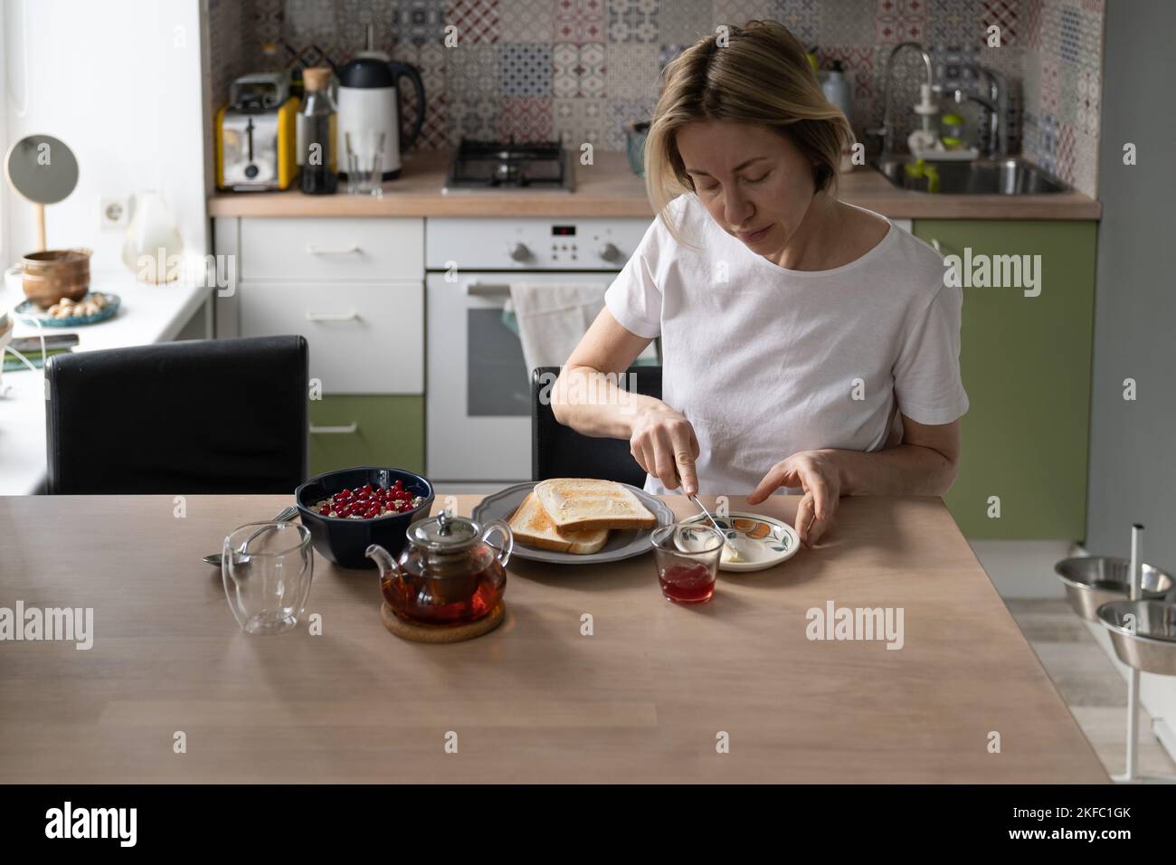 Mature woman prepares breakfast spreading toasts with butter for ...