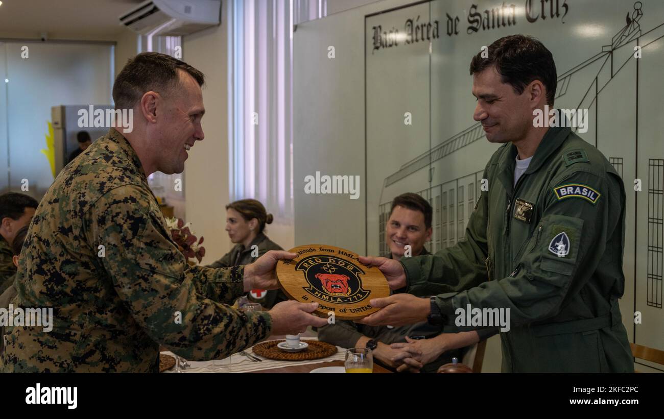 U.S. Marine Corps Lt. Col William C. Woodward, left, commander of Marine Light Attack Helicopter Squadron (HMLA) 773, Marine Forces Reserve, presents a gift to Capitao de mar e guerra Marcos de Oliveria Macedo (Colonel Brazilian Marine Corps), operations group commander at Santa Cruz Air Force Base, during exercise UNITAS LXIII in Rio de Janeiro, Sept. 5, 2022. The gift was given as a symbol of gratitude. UNITAS is the world’s longest-running annual multinational maritime exercise that focuses on enhancing interoperability among multiple nations and joint forces during littoral and amphibious Stock Photo