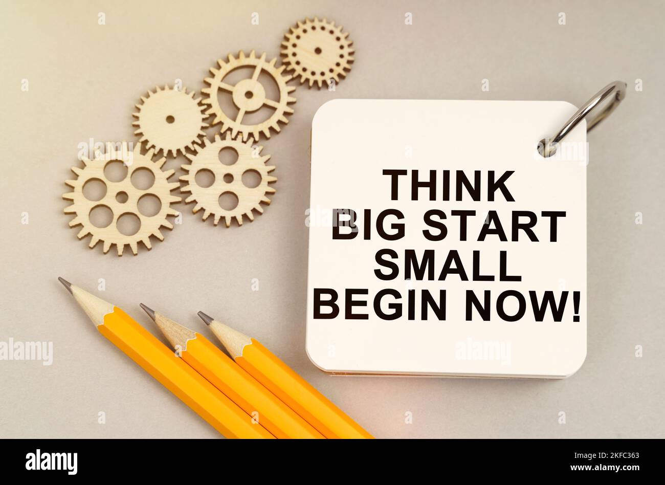 Business and finance concept. On the table are gears, pencils and a notebook with the inscription - Think Big Start Small Begin Now Stock Photo