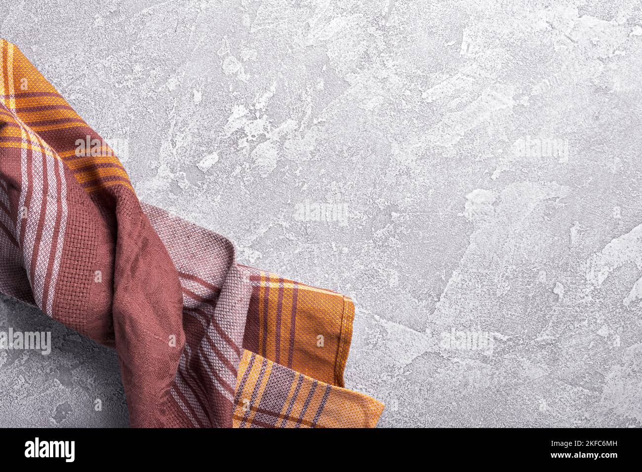 Top view of brown folded kitchen towel or serviette on grey concrete background Stock Photo