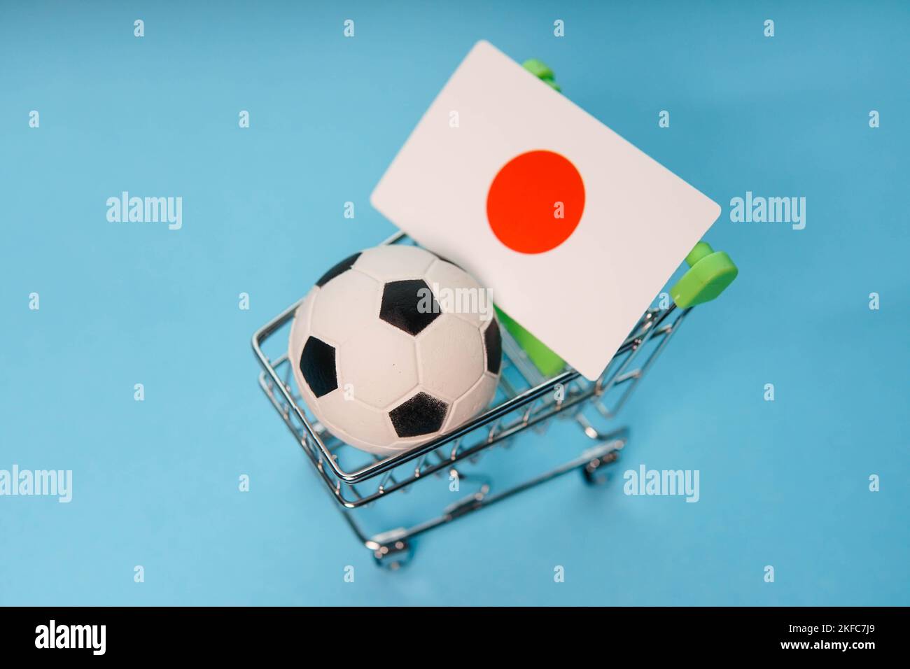 Soccer ball with Japanese flag in shopping cart on blue background. Football cup earnings. Stock Photo