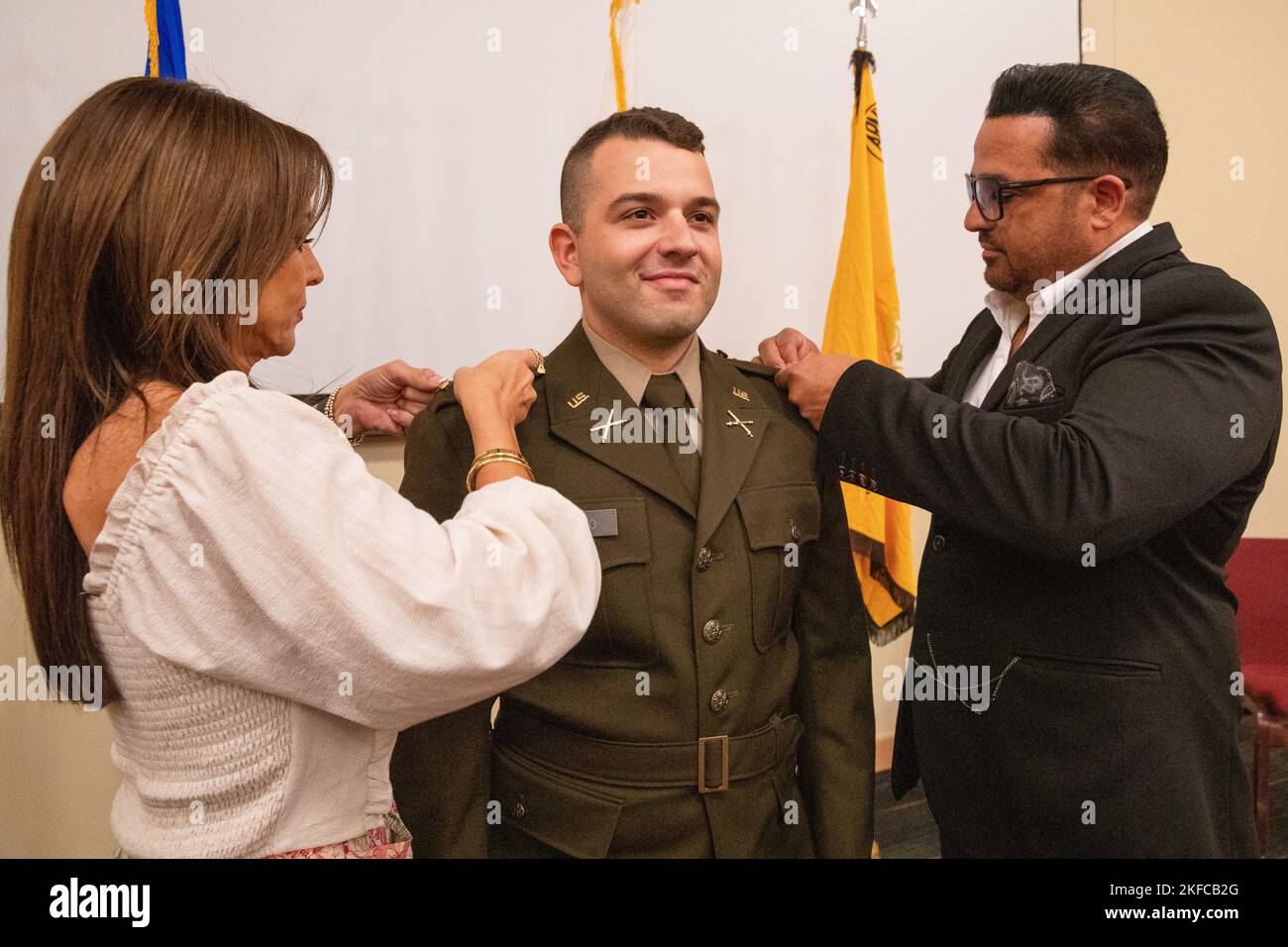 U.S. Army 2nd Lt. Michael Cotto stands at attention while his family, Israel Cotto and Elba Davila, pin on his second lieutenant rank insignia during a commissioning ceremony held inside the auditorium of the Regional Training Institute at Camp Nett, Niantic, Connecticut, Sept. 6, 2022. Cotto will be a field artillery officer. Stock Photo