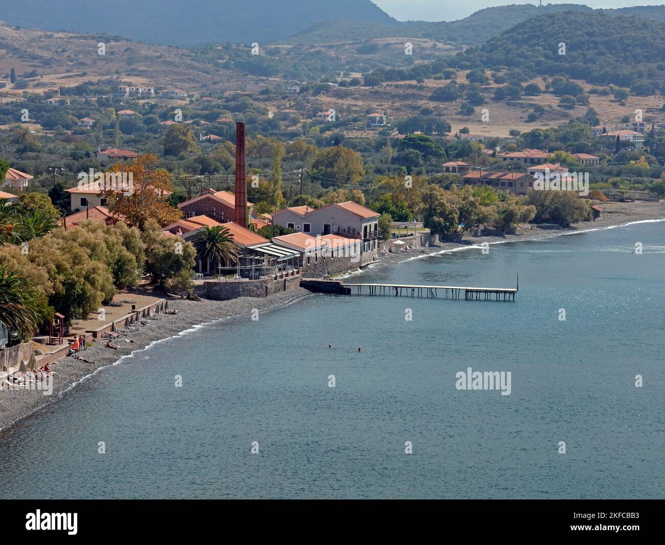 Former old olive oil factory with tall chimney and its own and jetty, now a restaurant. Molyvos town, Lesbos island, Greece. October 2022. Autumn Stock Photo
