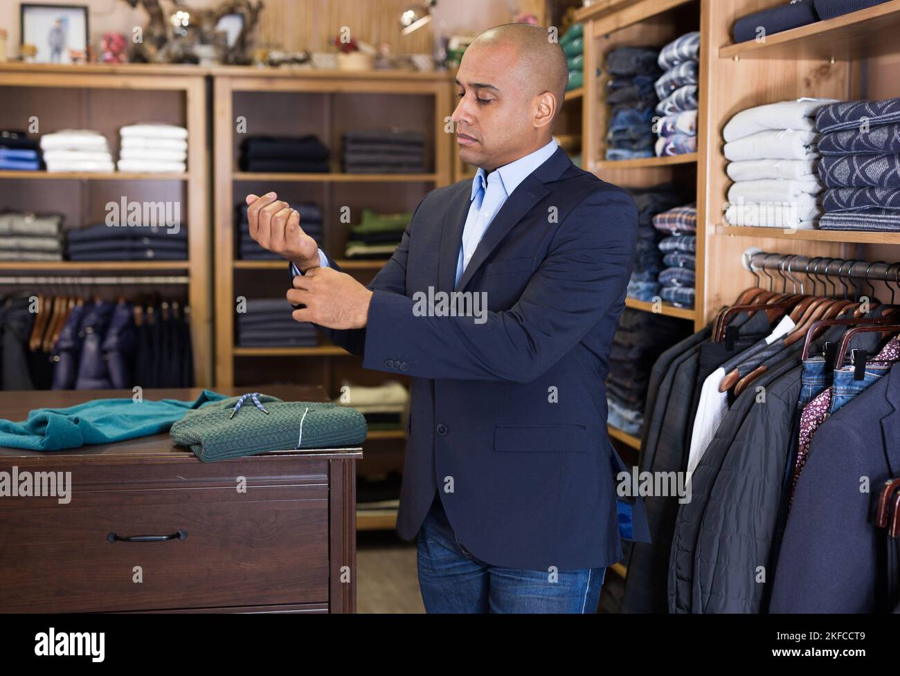 Man choosing suit jacket in clothing store Stock Photo - Alamy