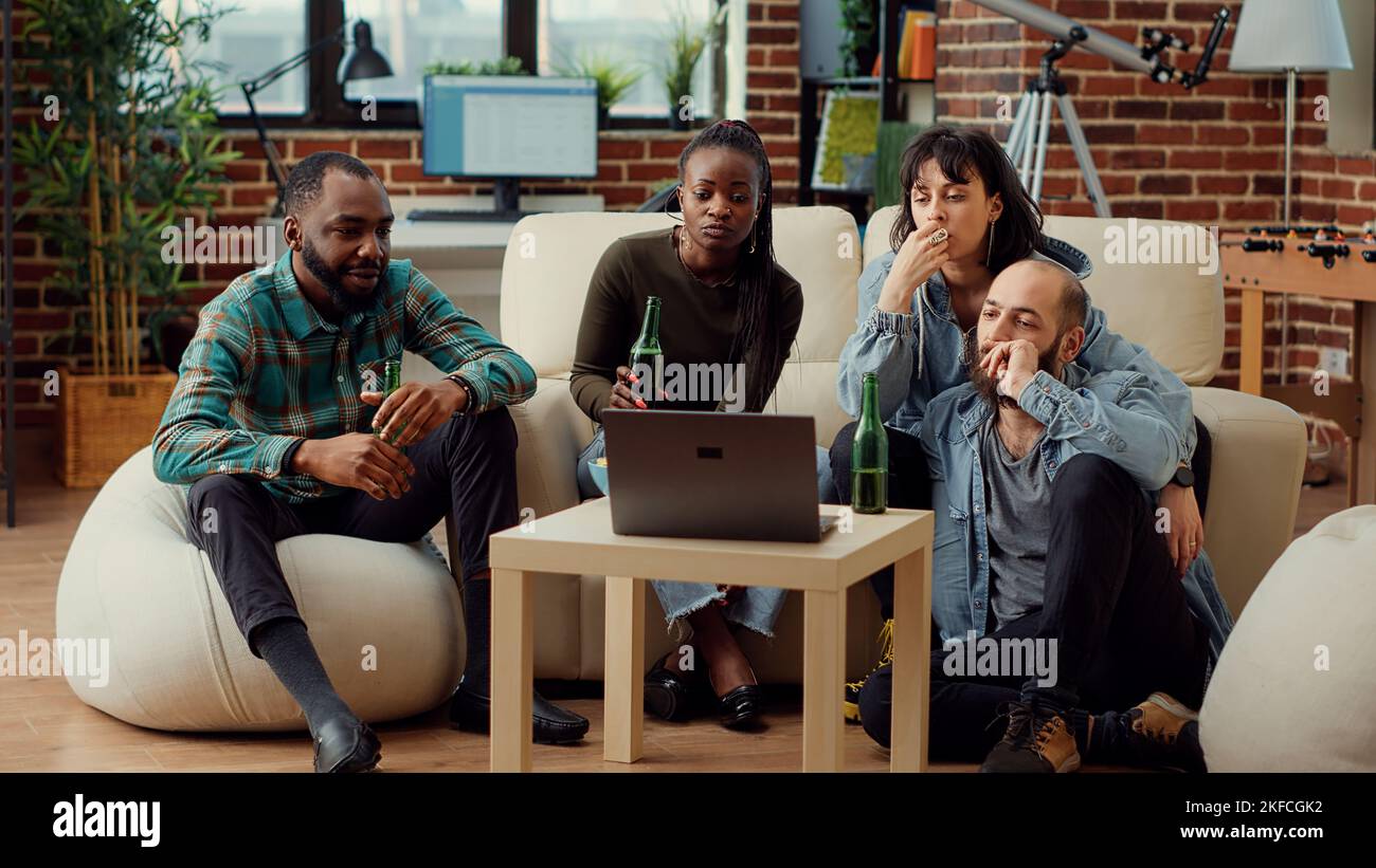 Diverse people watching video on laptop and talking at weekend hangout ...