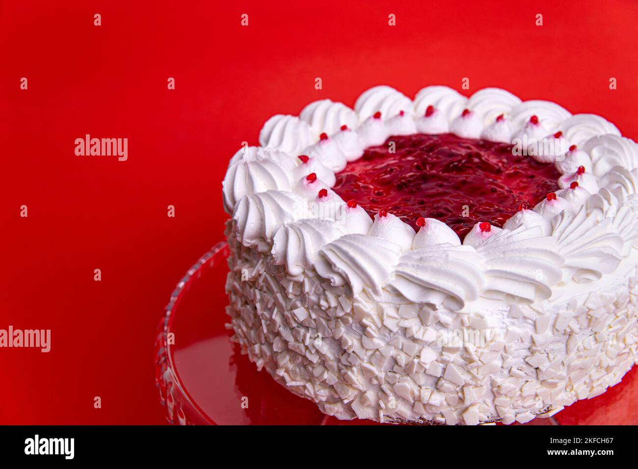 Cake with cherry isolated on white background. Piece of cheesecake with red fruits. White birthday cake on a red background. Cake with cherry jam and Stock Photo