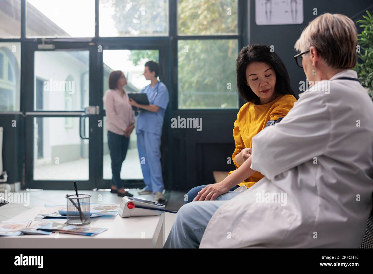 Old physician doing hypertension examination with tonometer in hospital ...