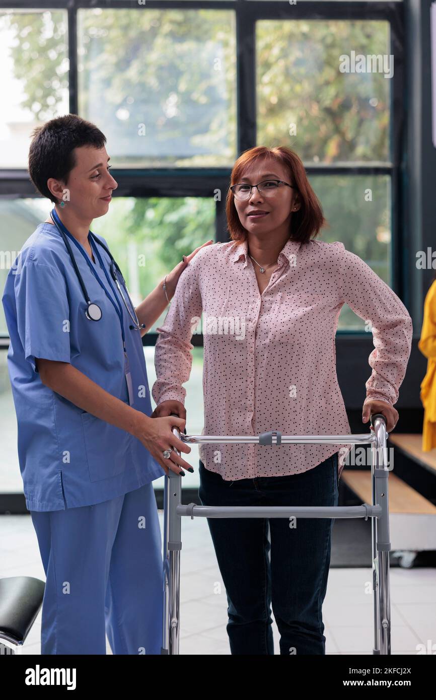 Health specialist supporting senior woman to walk with leg fracture