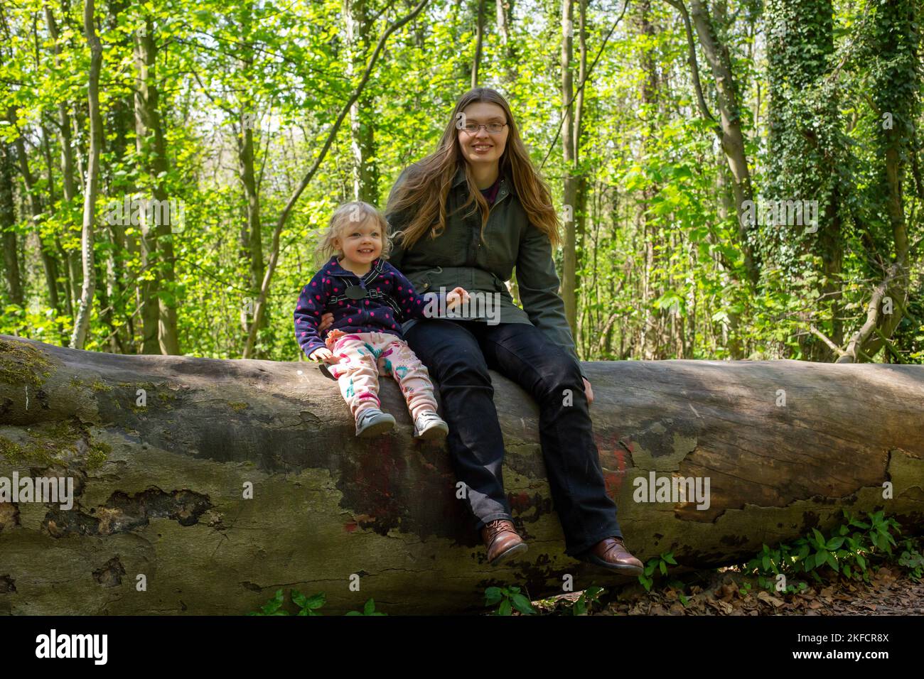 Mum and daughter sitting on a log in the woods Stock Photo Alamy