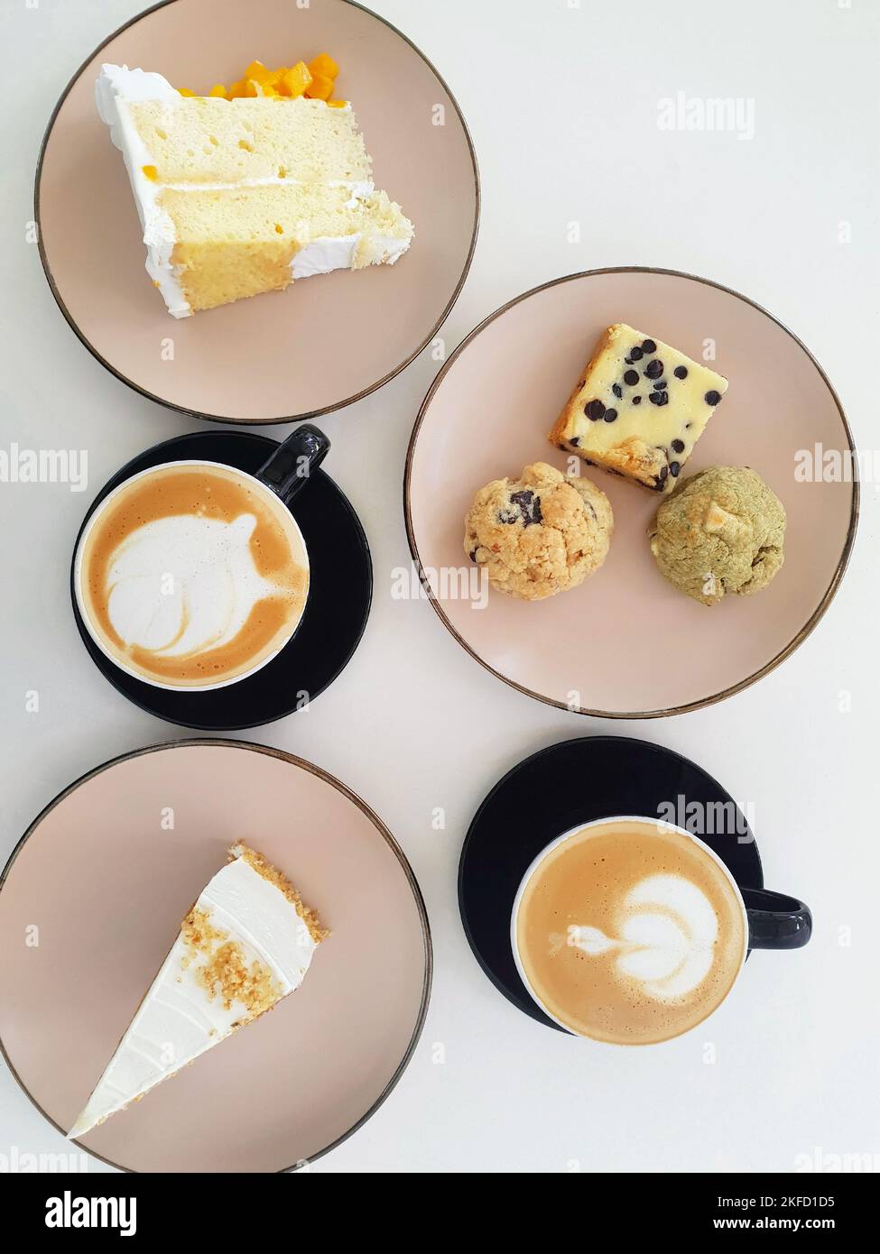 Minimalist flatlay of two warm coffees on cups plus cakes, cookies, and brownies on tiny plates