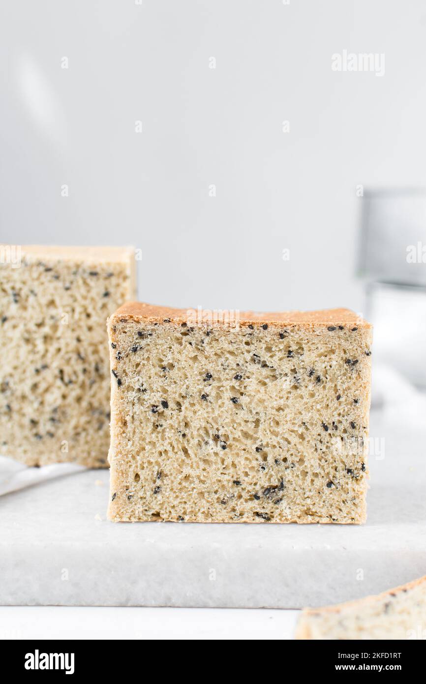 Black sesame seed bread on a white chopping board, poppy seed bread
