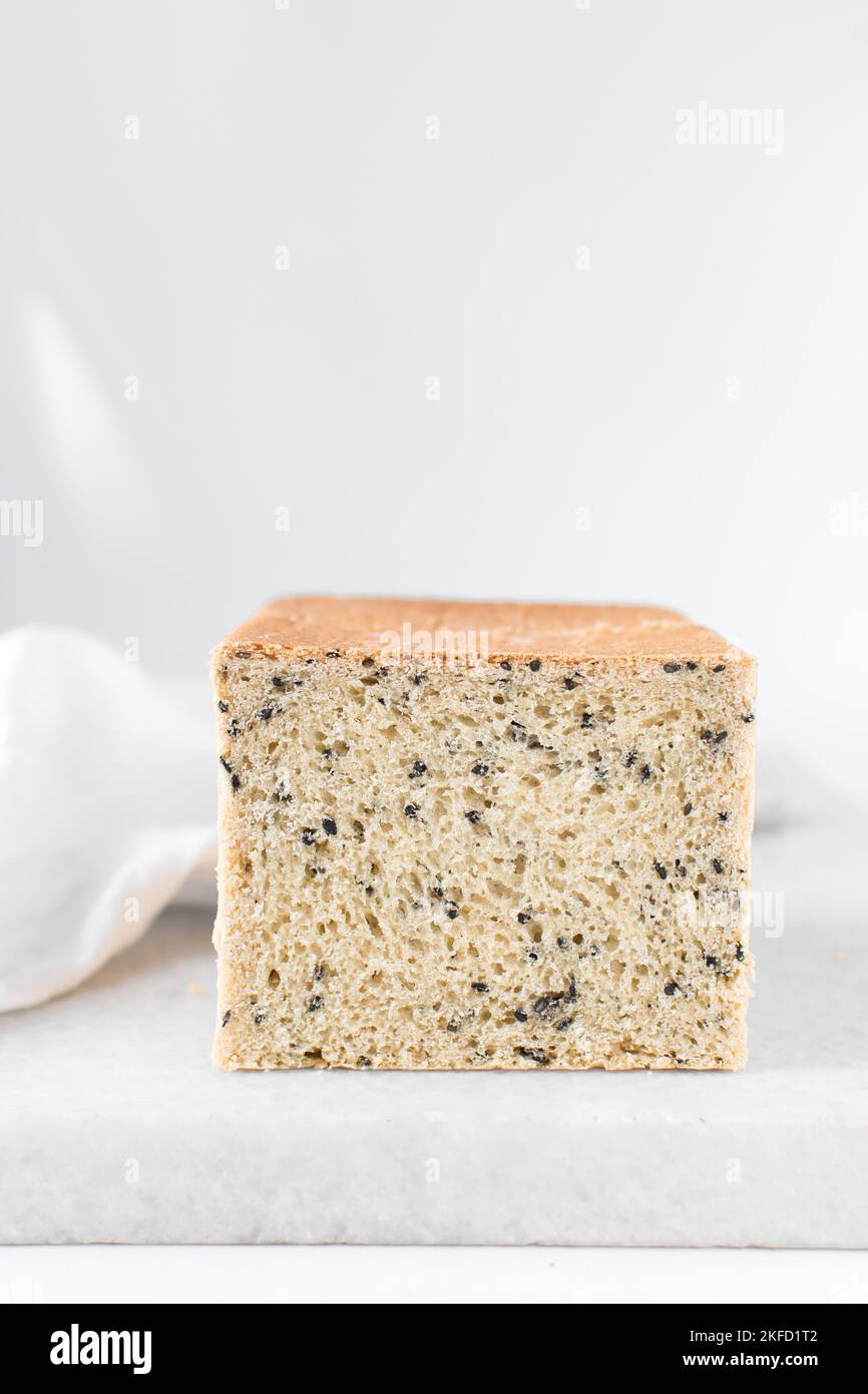 Black sesame seed bread on a white chopping board, poppy seed bread