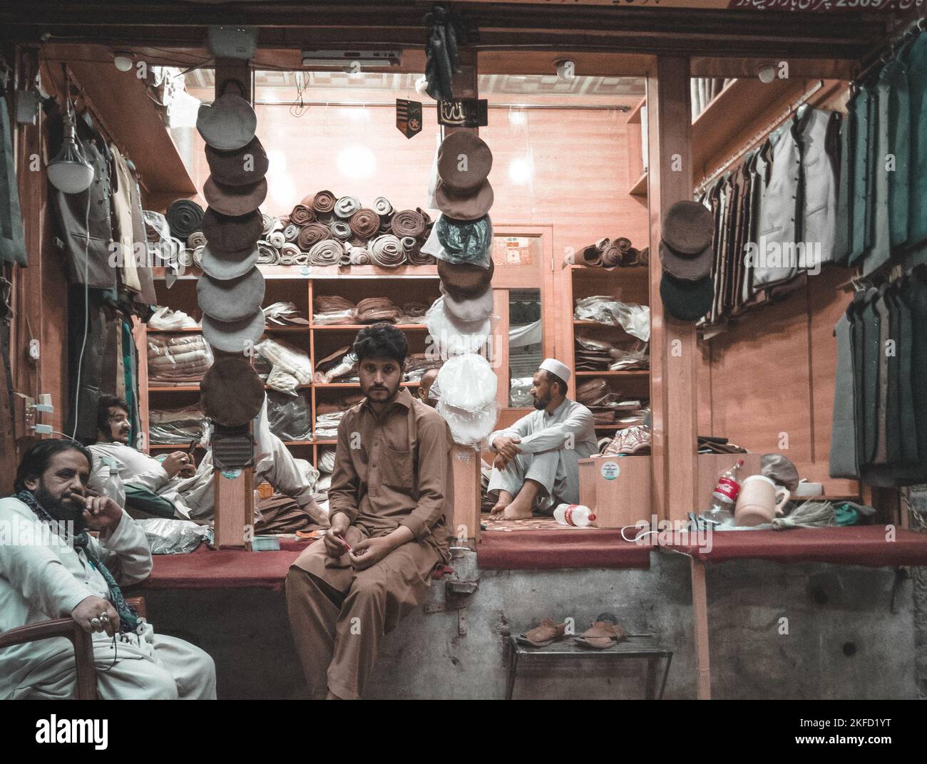 A clothing shop with traditional clothes and male sellers in it, Peshawar, Pakistan, view from