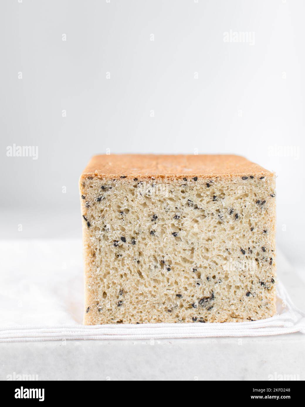 Black sesame seed bread on a white chopping board, poppy seed bread
