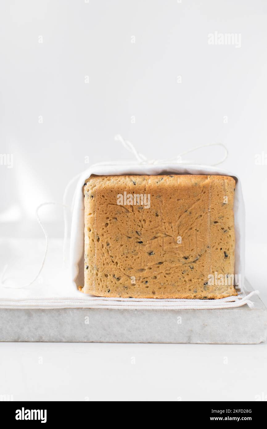 Black sesame seed bread on a white chopping board, poppy seed bread