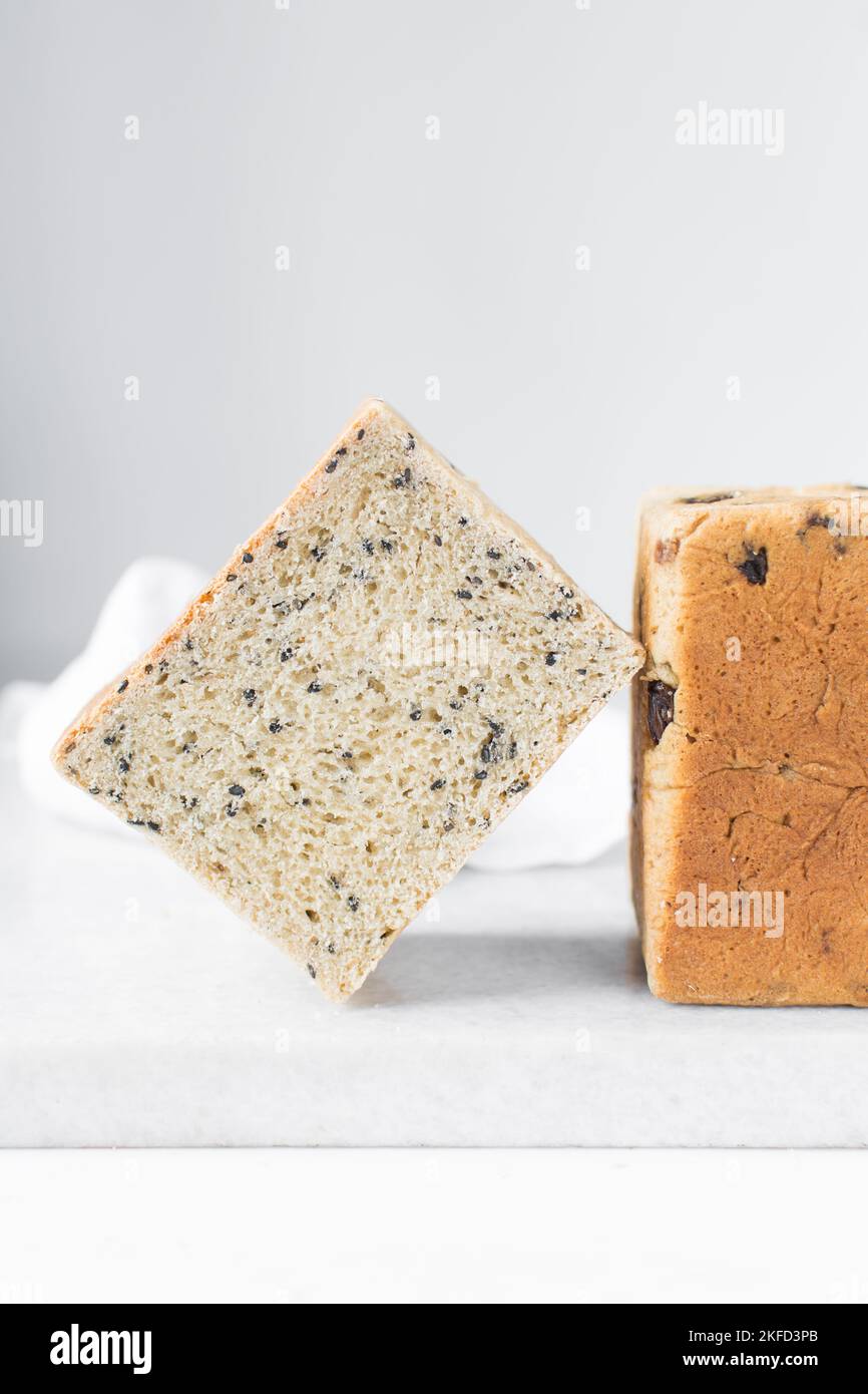 Black sesame seed bread on a white chopping board, poppy seed bread