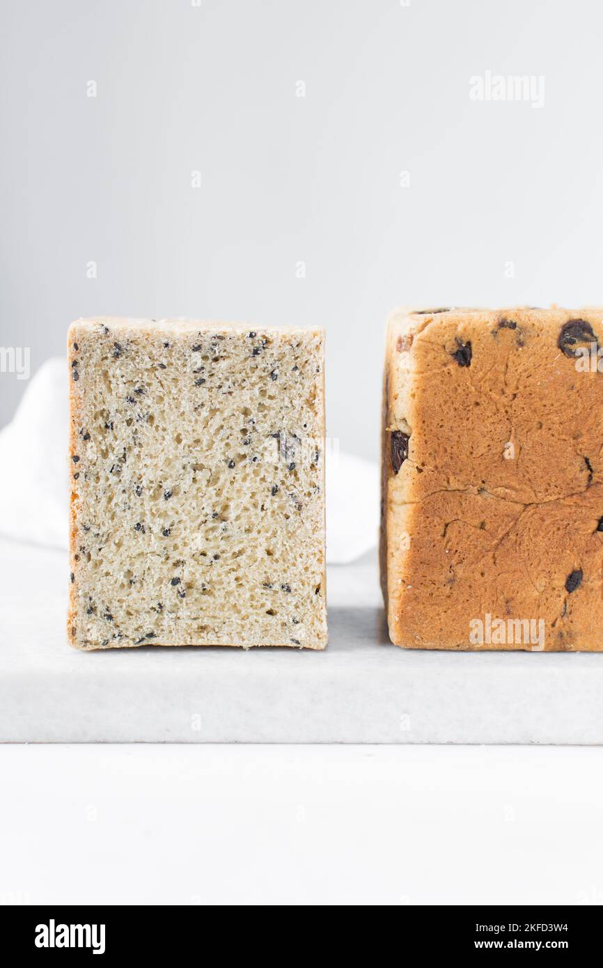 Black sesame seed bread on a white chopping board, poppy seed bread