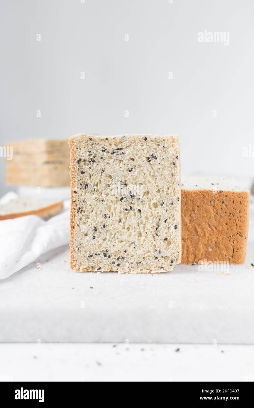 Black sesame seed bread on a white chopping board, poppy seed bread