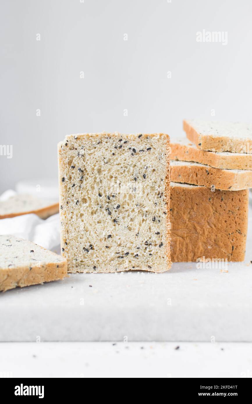 Black sesame seed bread on a white chopping board, poppy seed bread