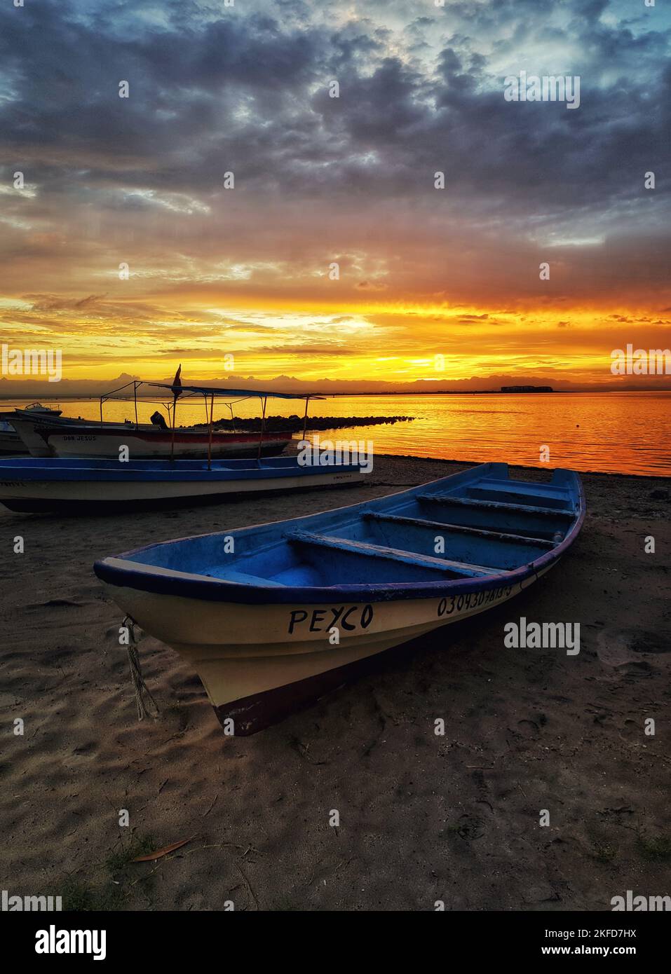 A vertical shot of boats with a scenic sunset across the sea in the ...