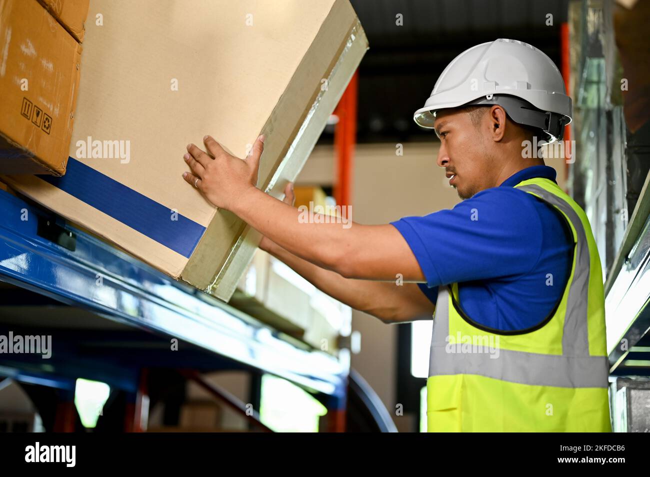 Smart millennial Asian male warehouse worker in his uniform working in