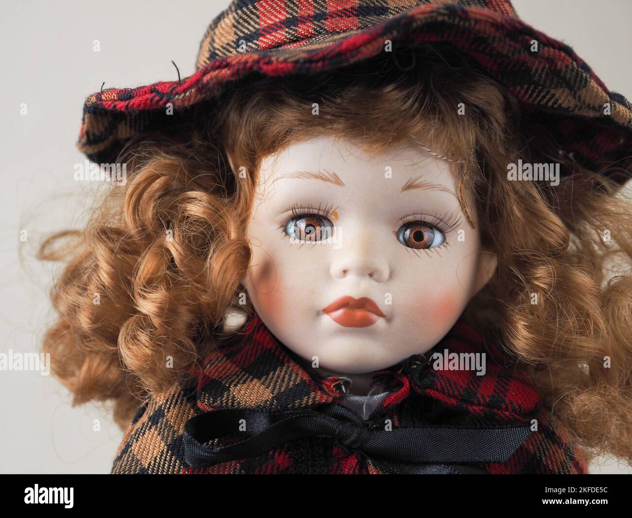 Vintage porcelain doll girl with brown eyes with red flowing curly