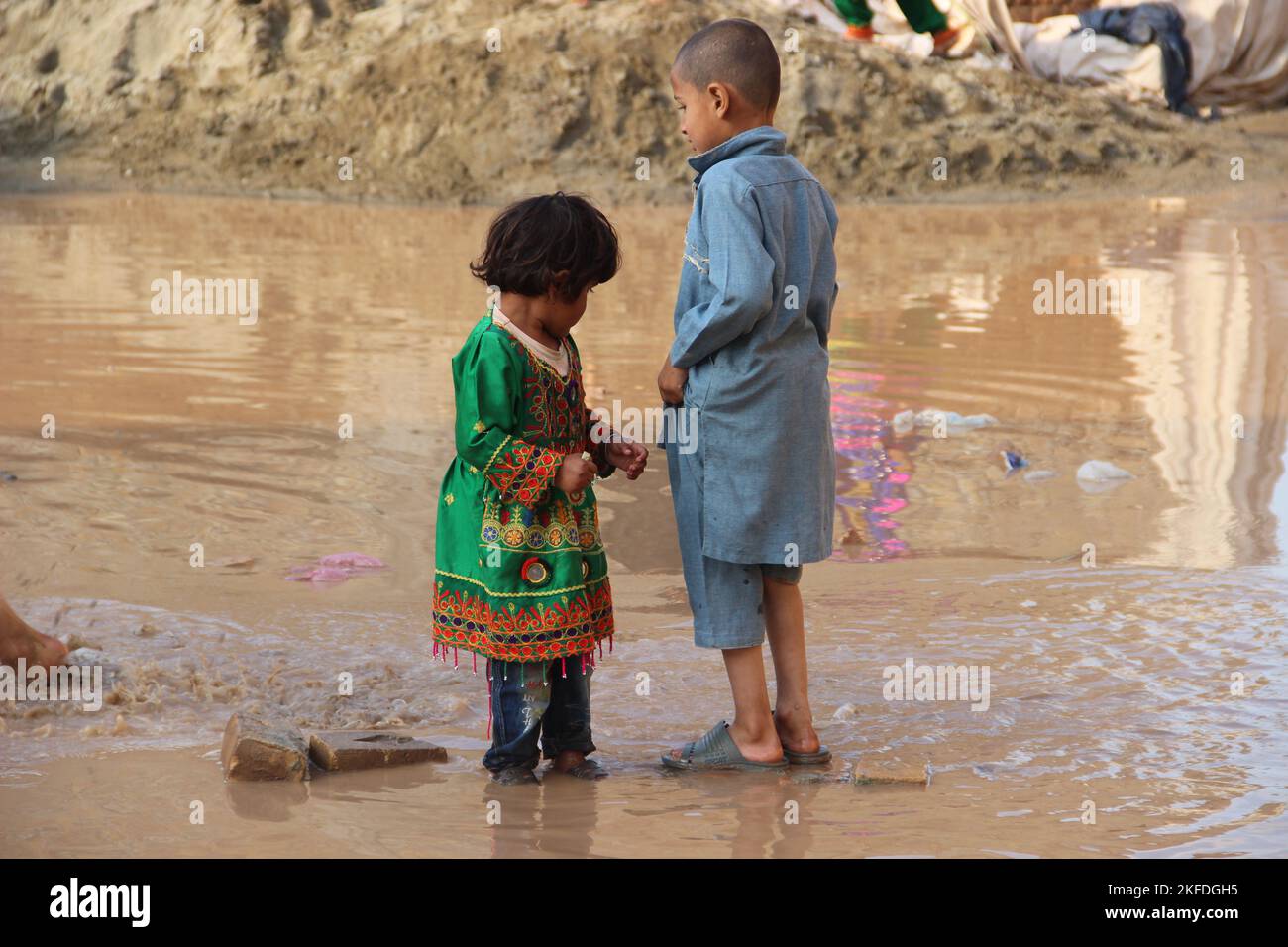 Khyber agency, Pakistan March 2020 kids, brother and sister playing in the rain water after rain in Pakistani traditional clothes Stock Photo