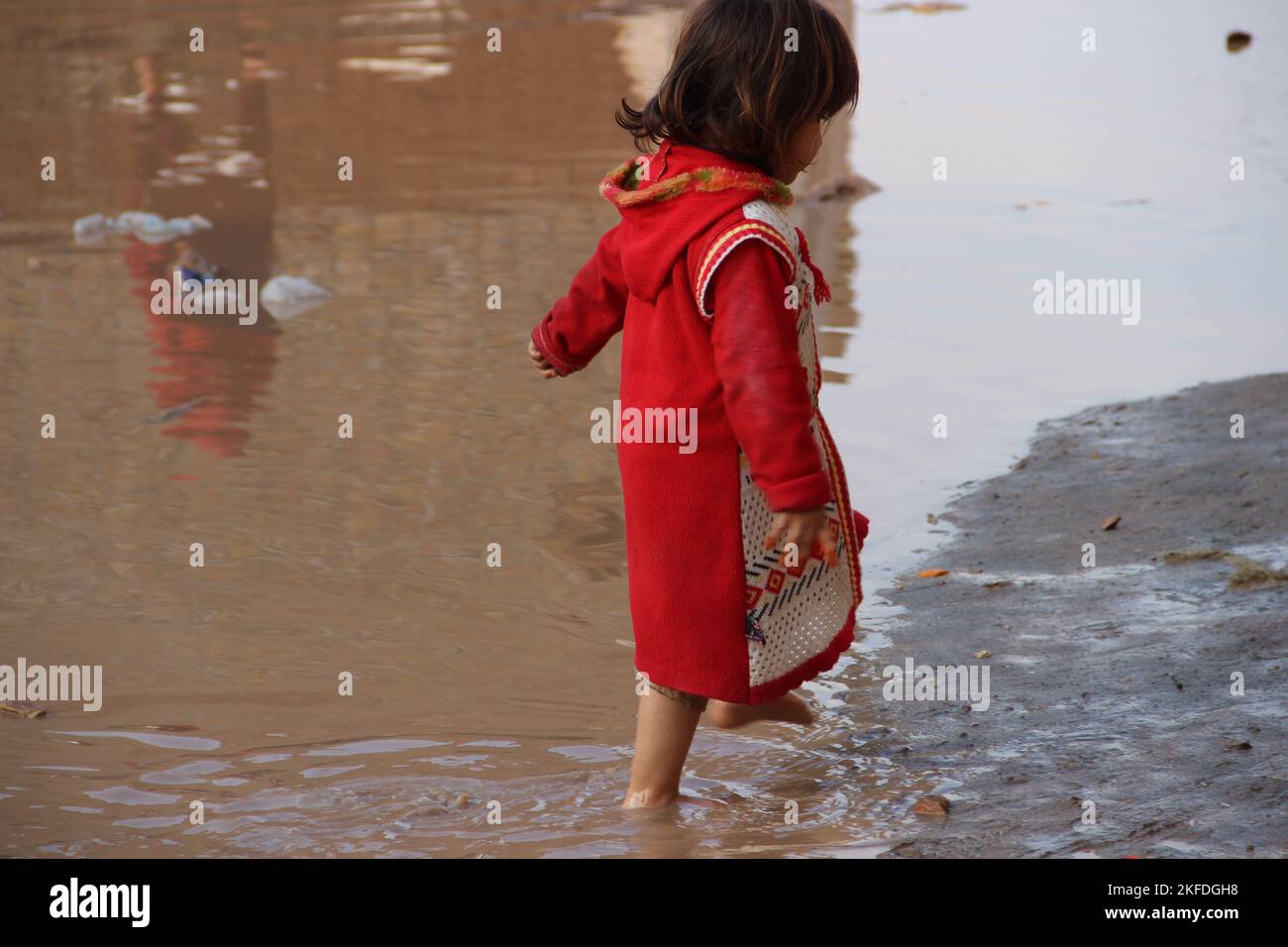 little cute girl, jumping in water after rain, muddy water.khyber agency, Peshawar, pakistan.april 2022. Stock Photo