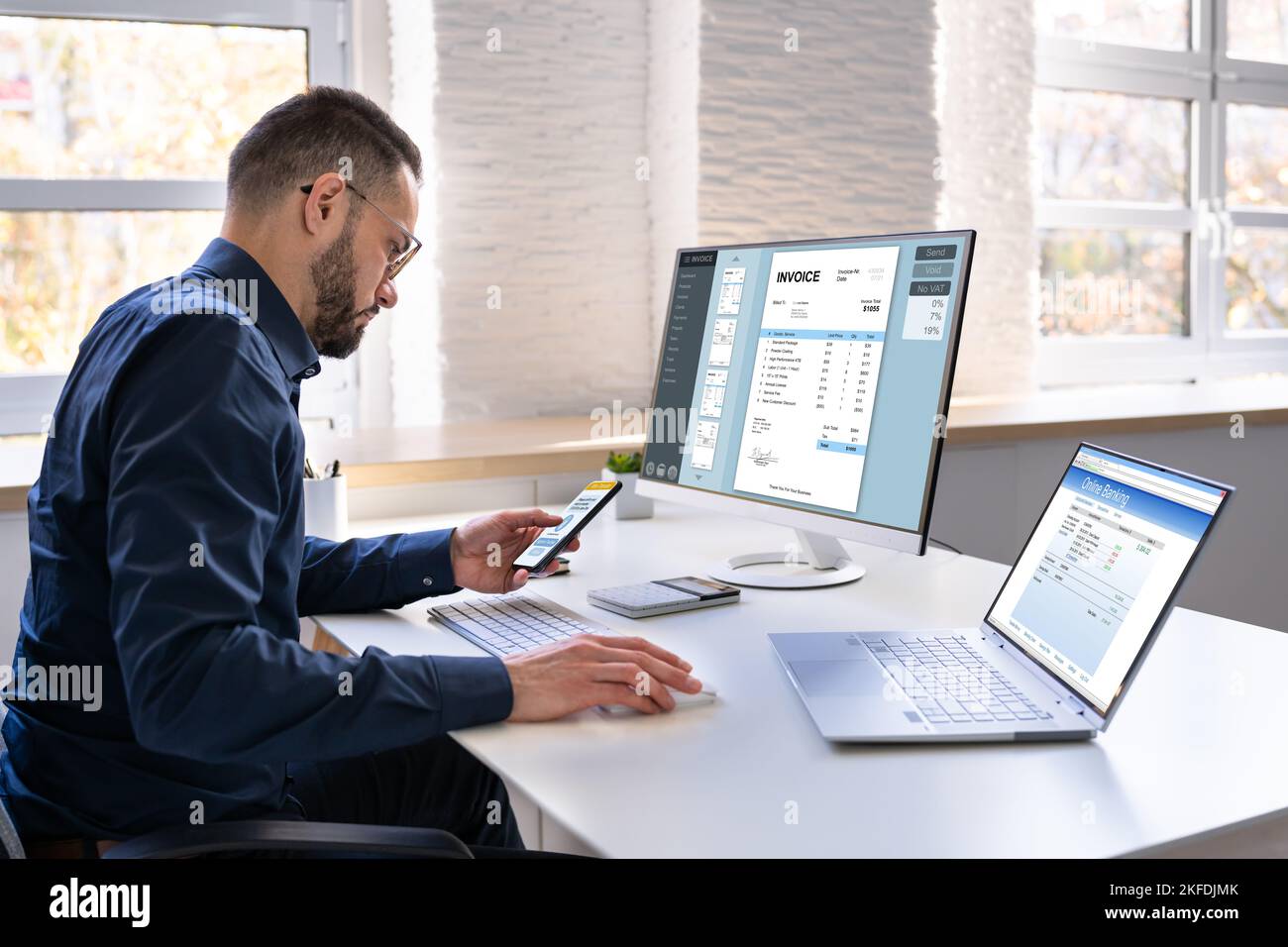 Young Businessman Looking At Invoice While Doing Online Banking On Computer Stock Photo