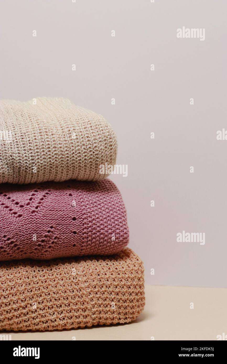 stack of folded knitwear, minimal lifestyle, capsule wardrobe, copy