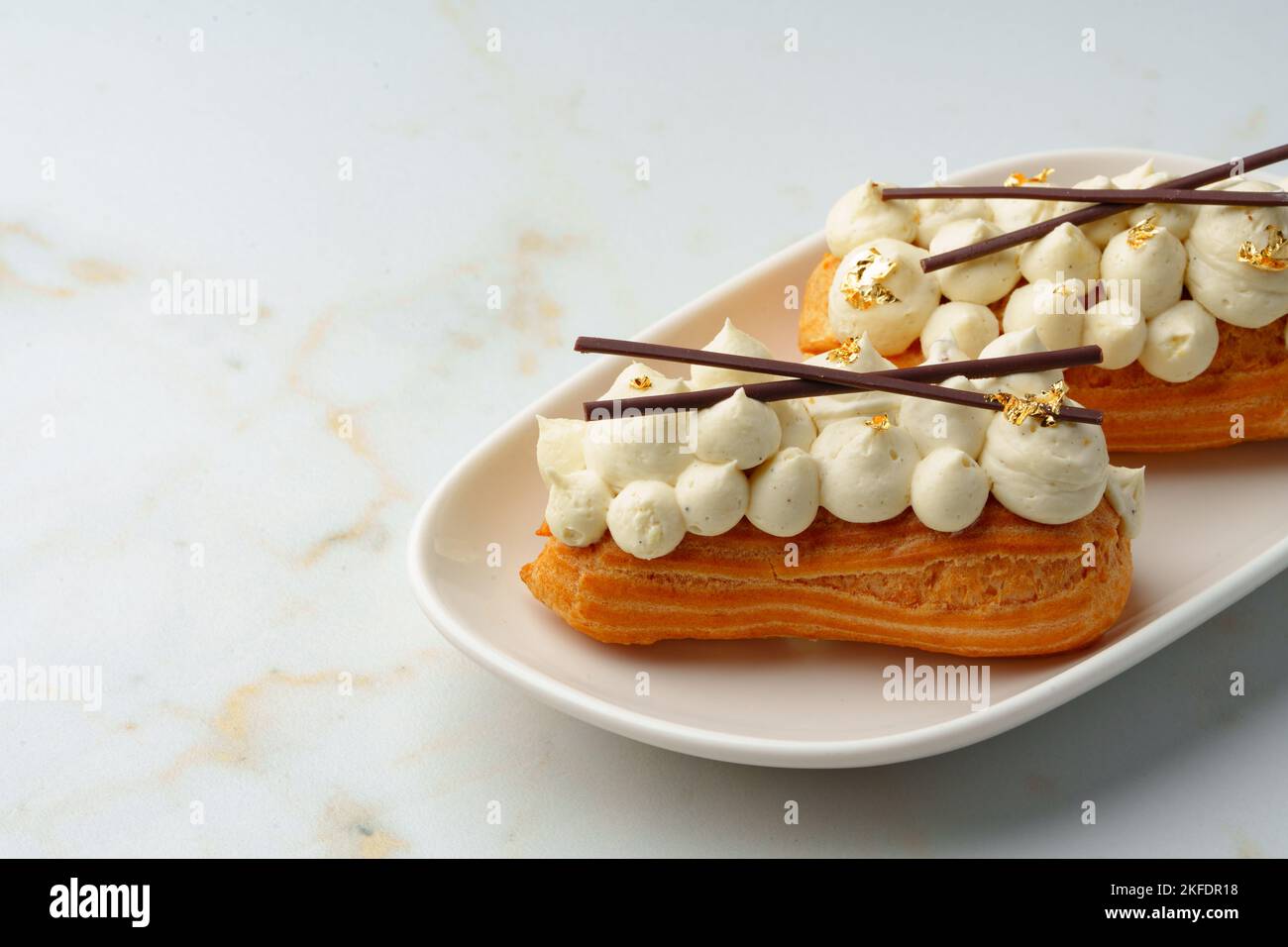Two eclairs with white custard on whhite plate Stock Photo