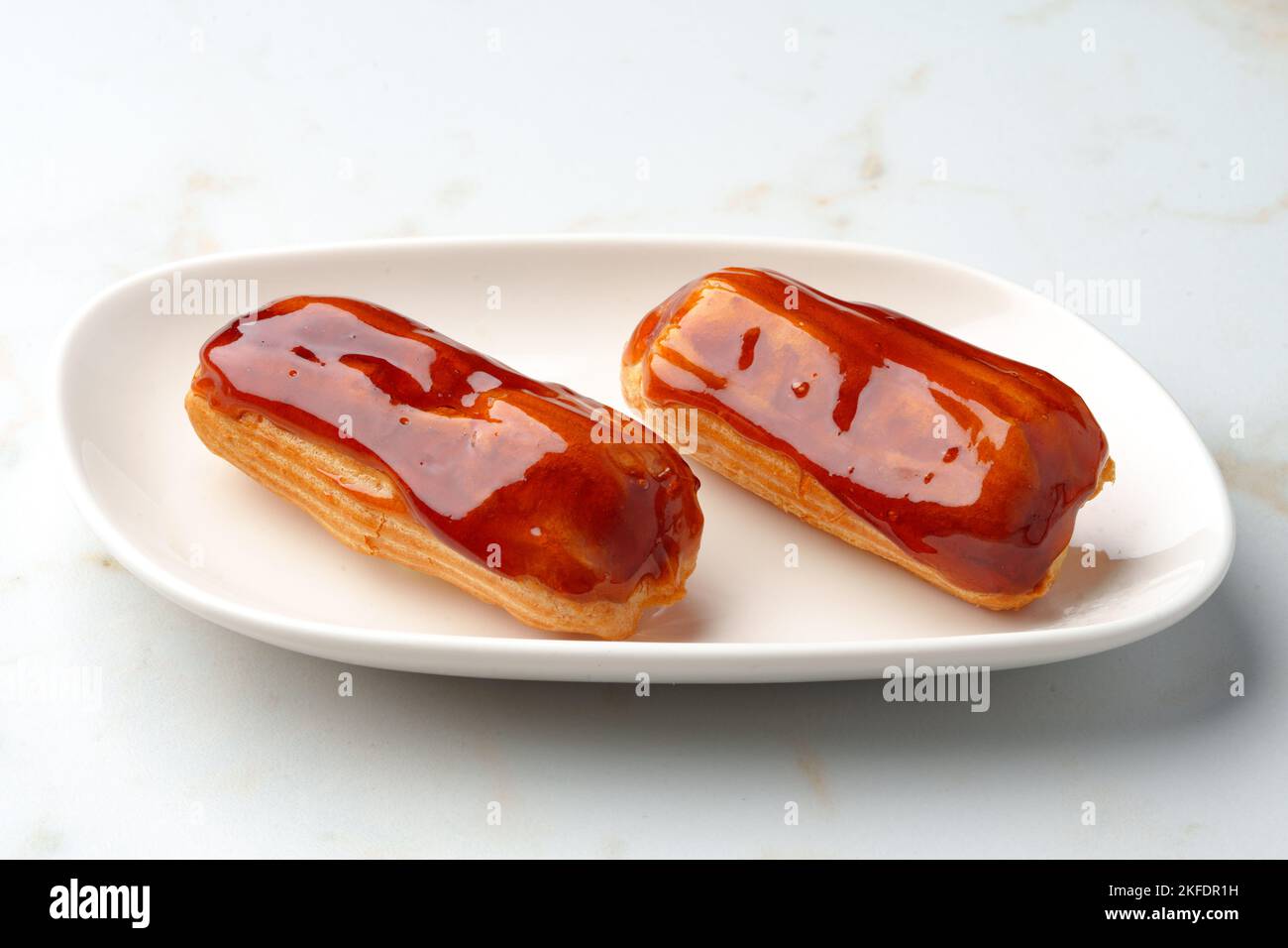 Two caramel eclairs on a white plate Stock Photo