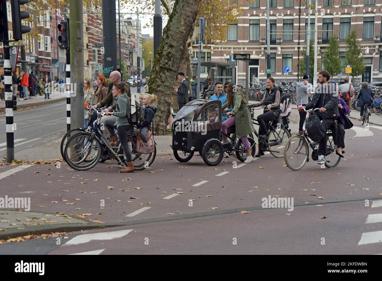 People on bikes waiting to cross a road junction in Amsterdam, Netherlands - Stock Image