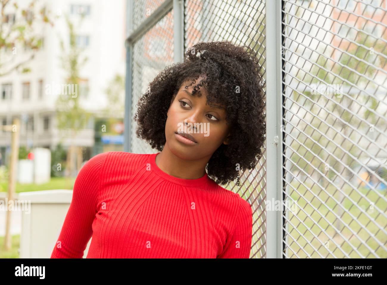 pensive african american young woman leaning on a fence Stock Photo