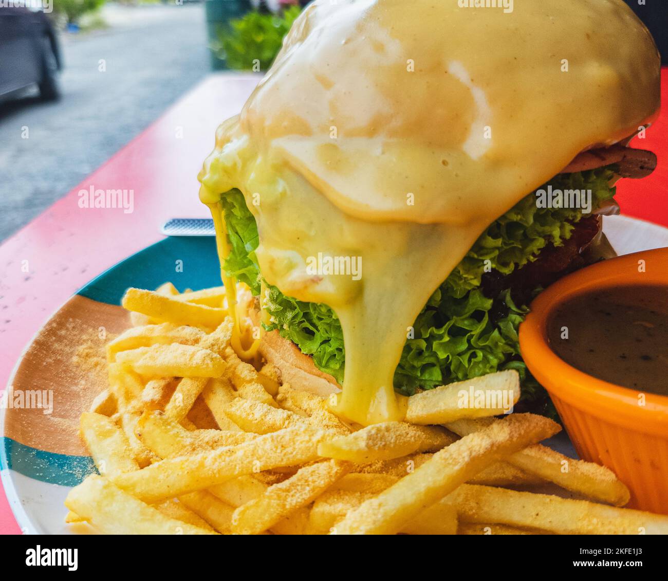 Beef cheeseburger with melted cheese served with black pepper sauce and fries. Stock Photo