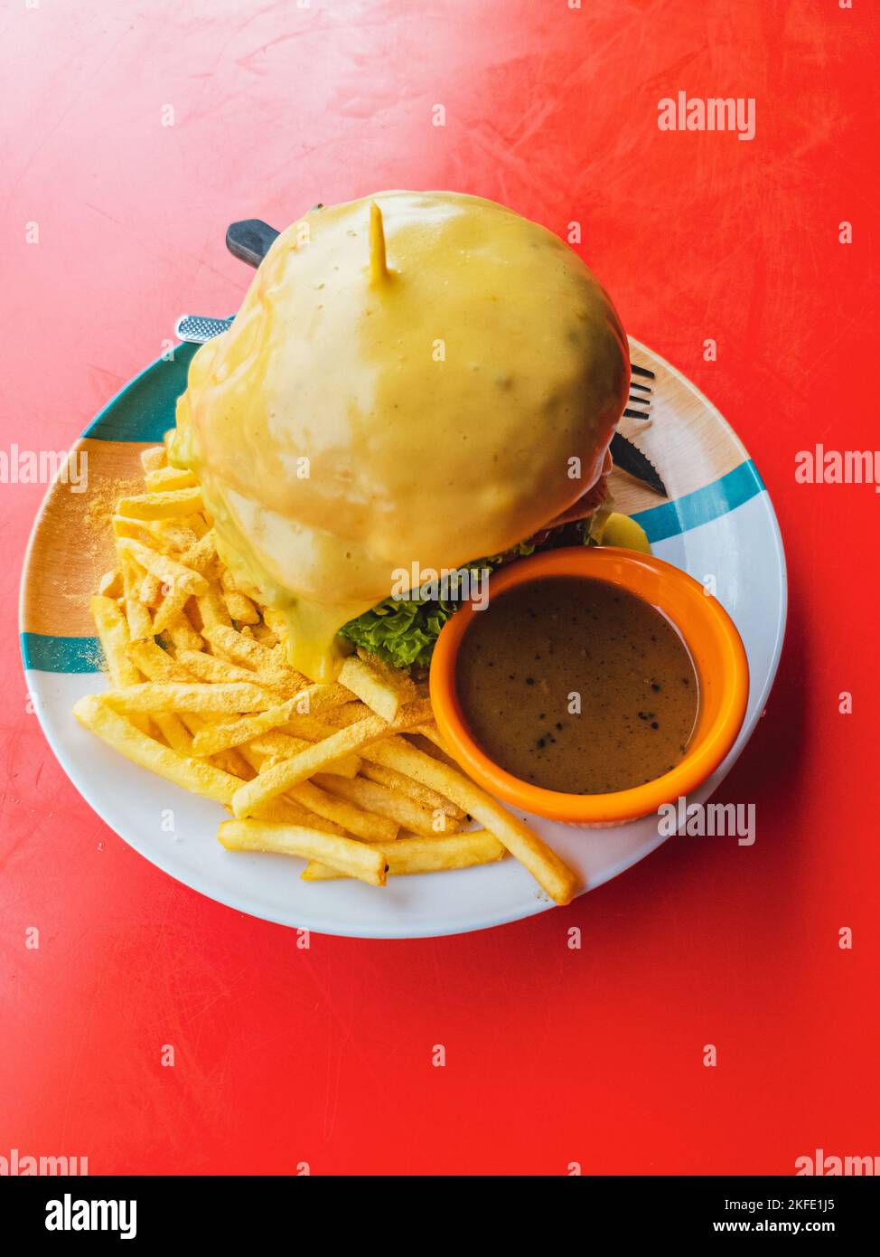 Beef cheeseburger with melted cheese served with black pepper sauce and fries. Stock Photo
