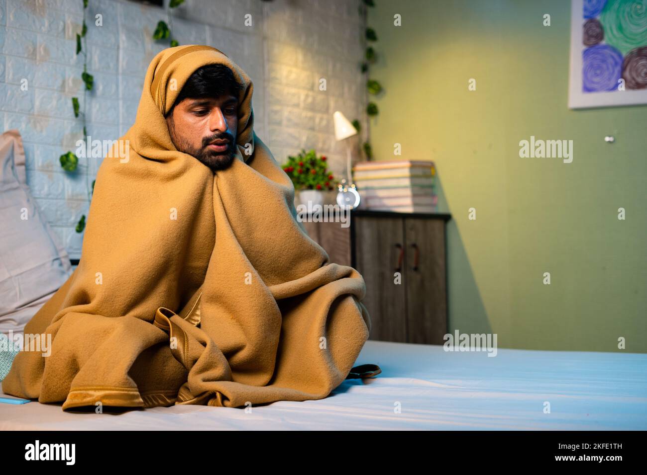 Shivering young man woke at night due to freezing cold at night on bedroom during winter - concept of sick, fever and unwell. Stock Photo