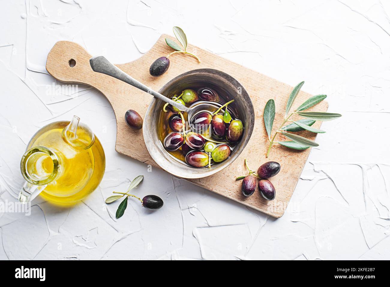 Olive oil in bowl with fresh olives fruit and olive branch on white background close up Stock Photo
