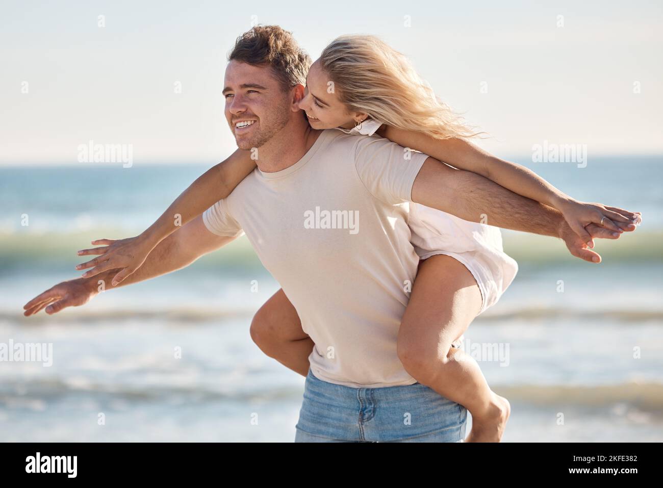 Couple, freedom and love at the beach, together and piggyback on adventure with travel and ocean. Trust, relationship and man with happy woman Stock Photo