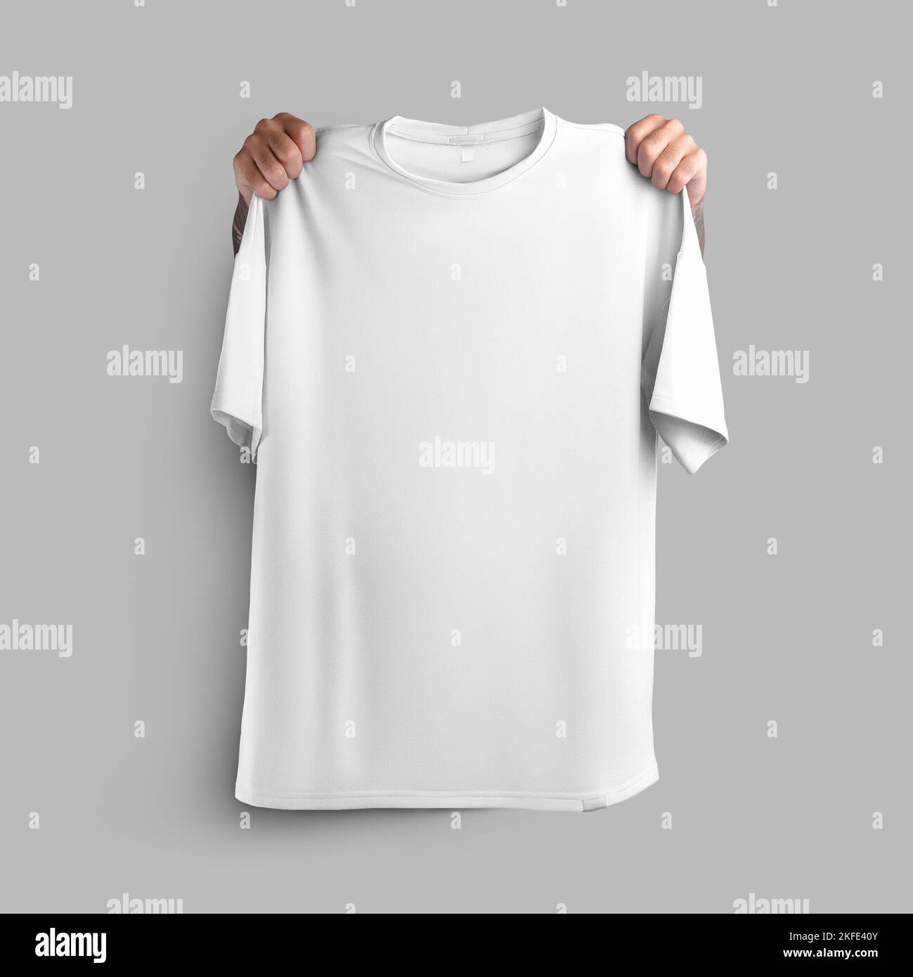 Mockup of white oversize t-shirt, clothes held in hands by shoulders, front view, for design, pattern, for advertising in online store. Template of sp Stock Photo
