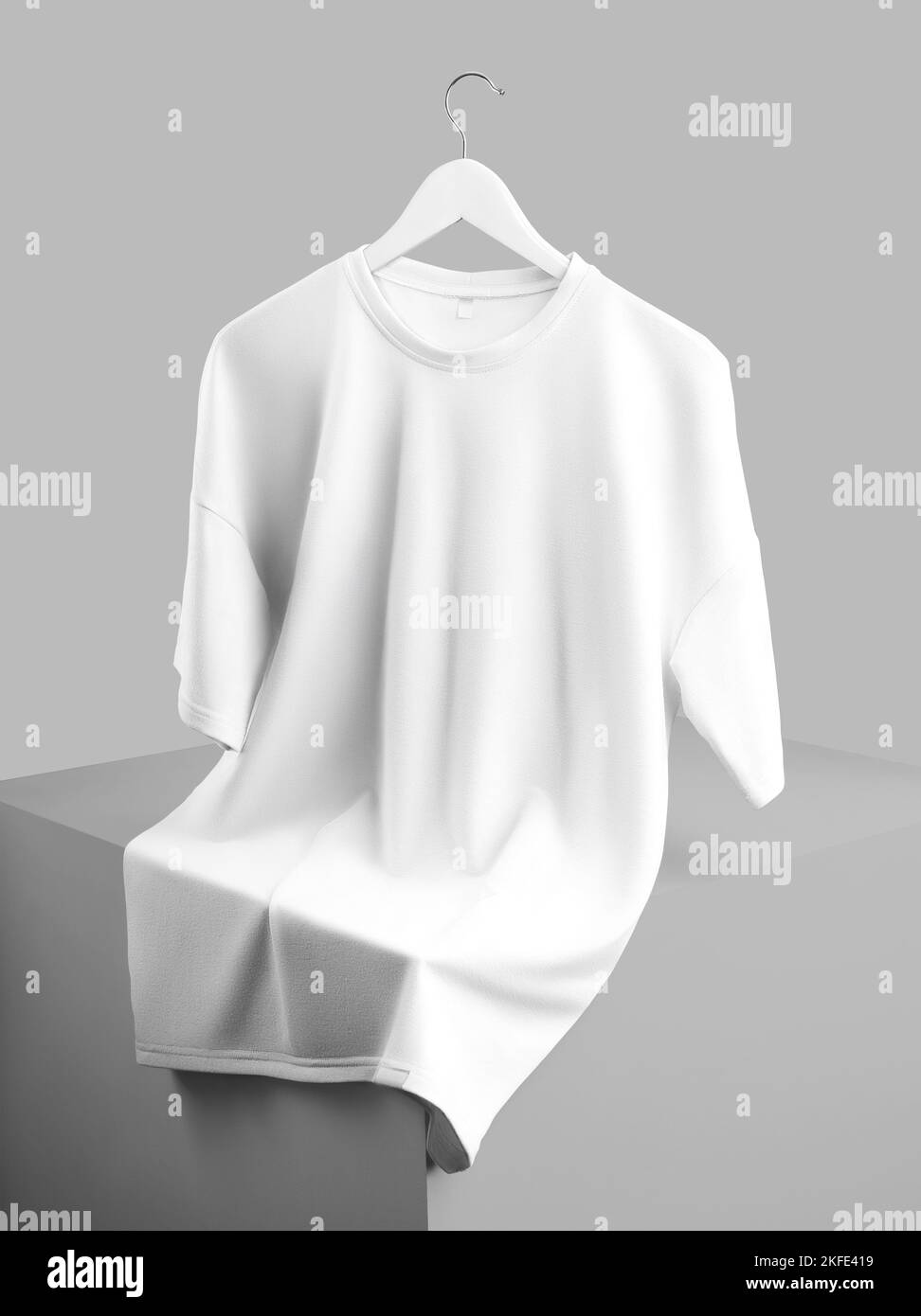 Mockup of an oversized white t-shirt hanging on a hanger, laid out over a cube, front view, isolated on background. Blank fashion apparel template wit Stock Photo