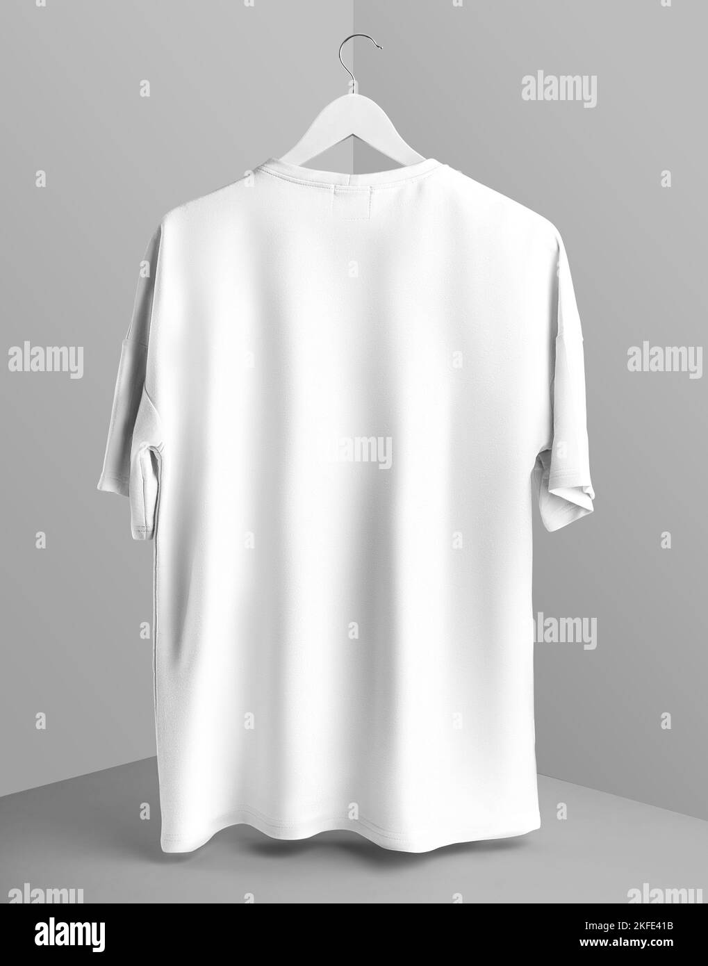 Mockup of an oversized white t-shirt hanging on a hanger above a cube, back view, with space for design, pattern, online store ad. Template of stylish Stock Photo