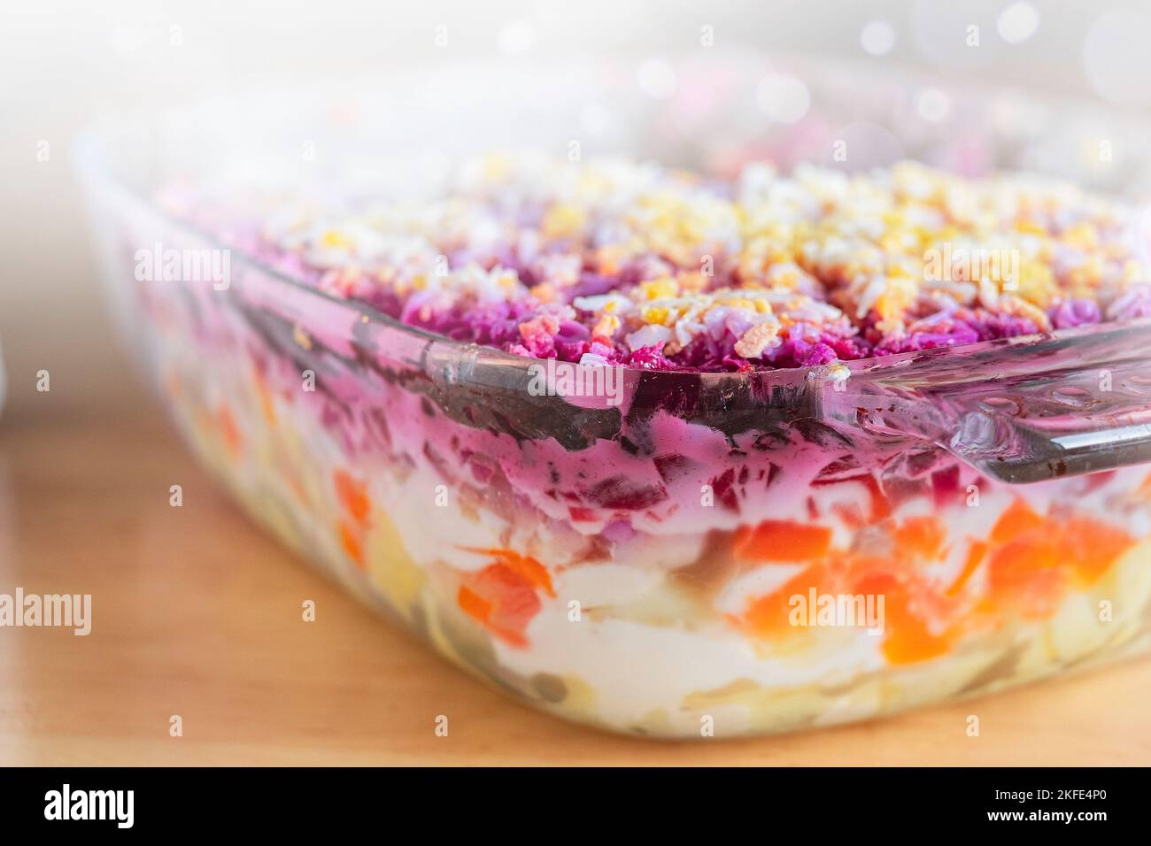 Layered salad herring under fur coat on table. Portion of traditional
